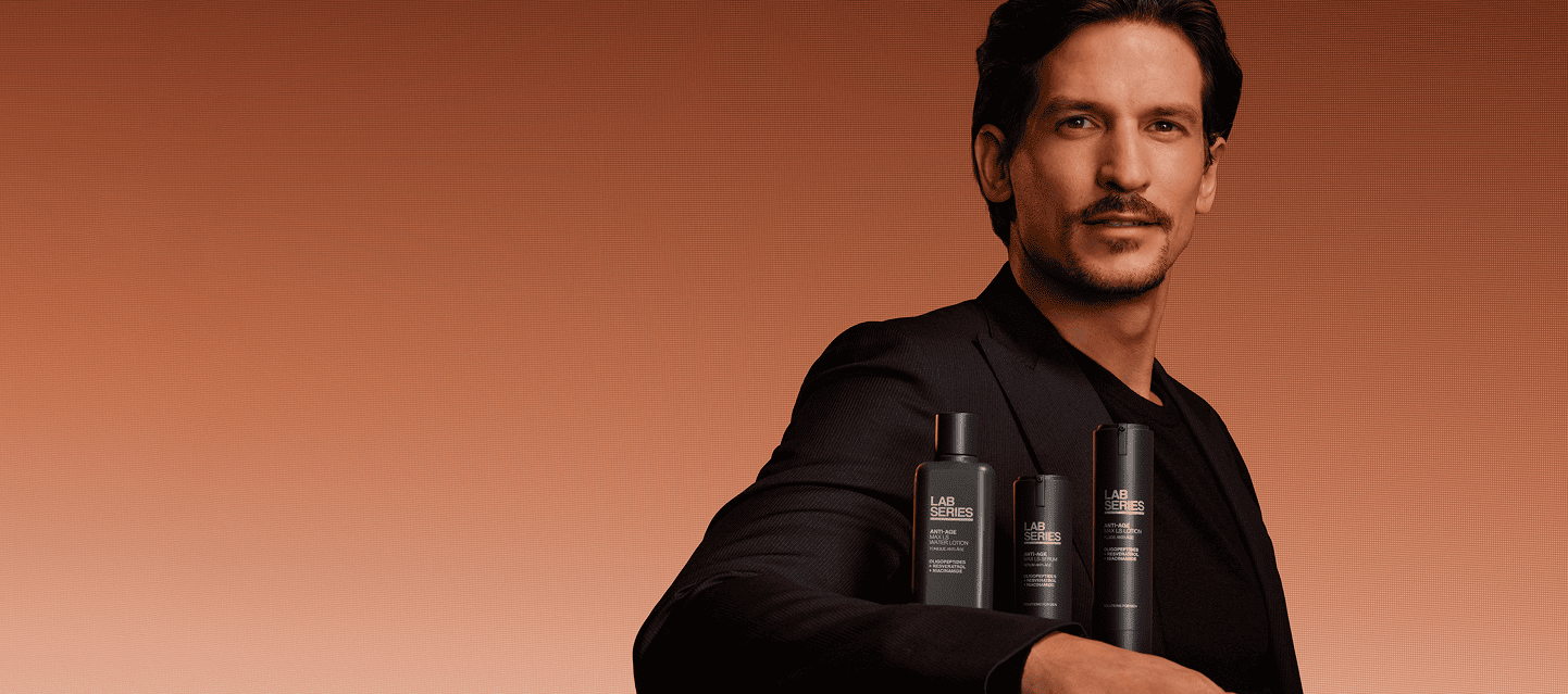 Person holding three sleek black skincare bottles.